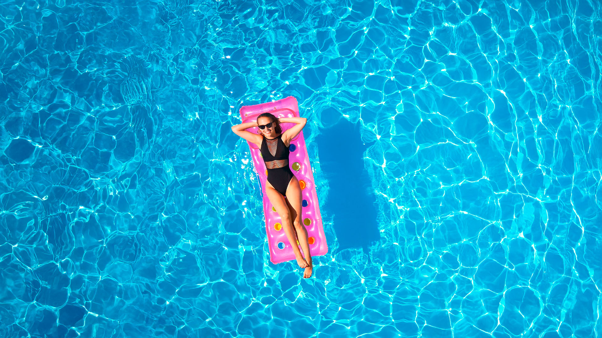 woman on pink floaty in the middle of the pool